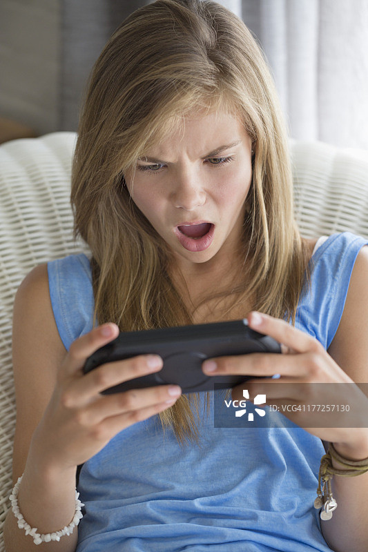 女孩玩电子游戏时面露惊讶图片素材