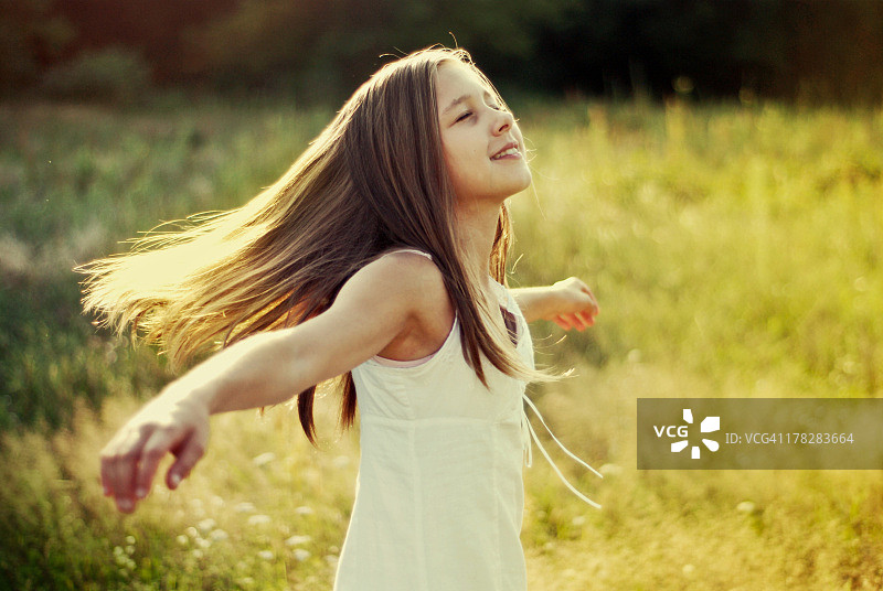 阳光明媚的草地上站立的少女图片素材