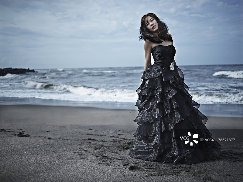 身穿黑色连衣裙的女人在海滩上图片素材