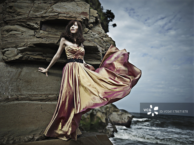 在海滩上穿着橙色连衣裙的女人图片素材