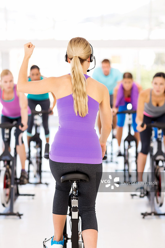 教练在健身房里激励学员骑自行车图片素材