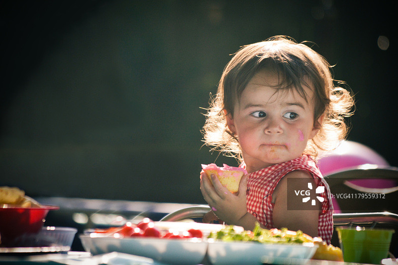 在聚会上吃纸杯蛋糕的小女孩图片素材