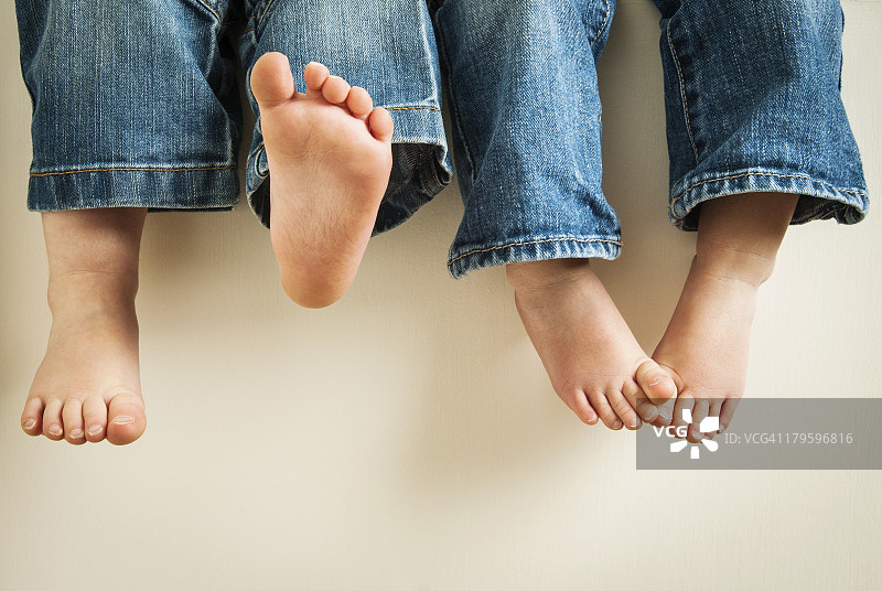 穿着牛仔裤摇晃脚的两个孩子的腿图片素材