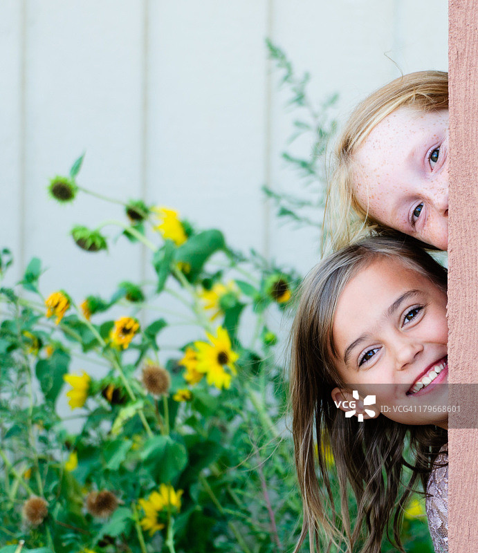 两个女孩从木桩后探头图片素材