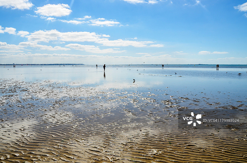 在退潮时沿着海滩行走的人们图片素材