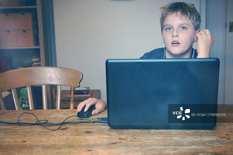 戴着耳机使用笔记本电脑的男孩图片素材