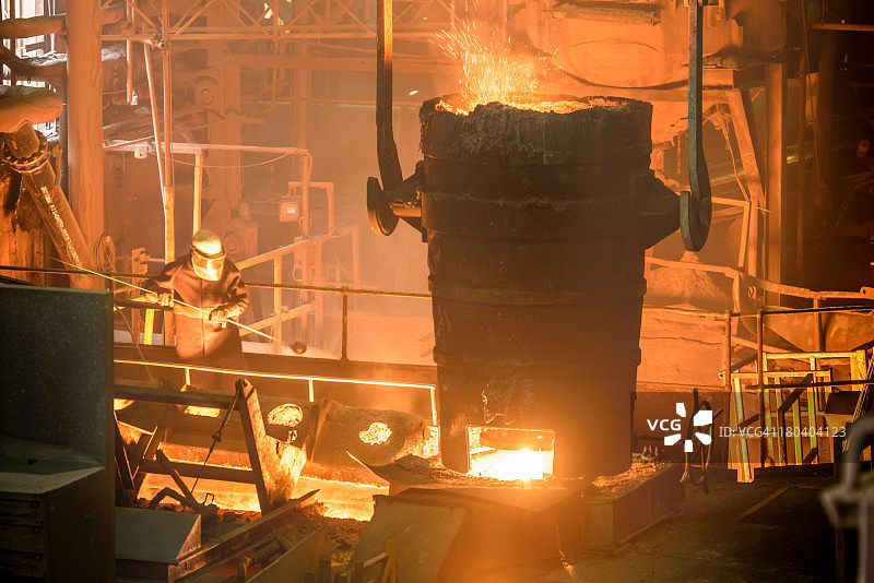 工业铸造厂中工人用勺子倾倒钢水图片素材