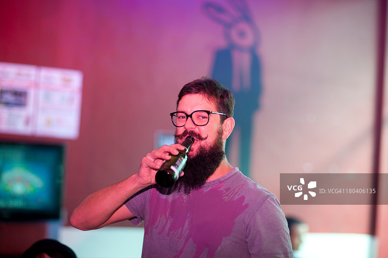 在酒吧里喝瓶装啤酒的男人肖像图片素材