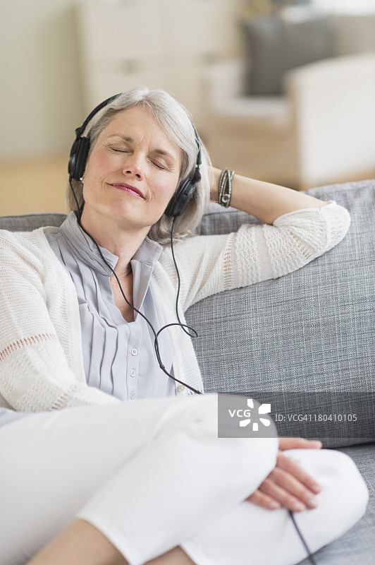 美国新泽西州泽西市，年长的女人坐在沙发上听音乐图片素材