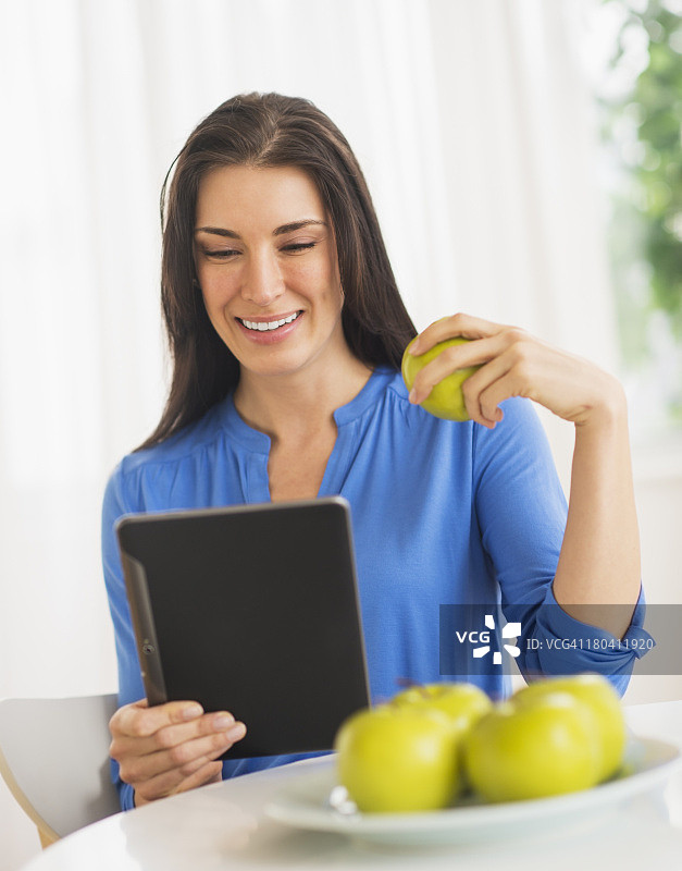 美国新泽西泽西市：女子吃苹果并使用平板电脑图片素材