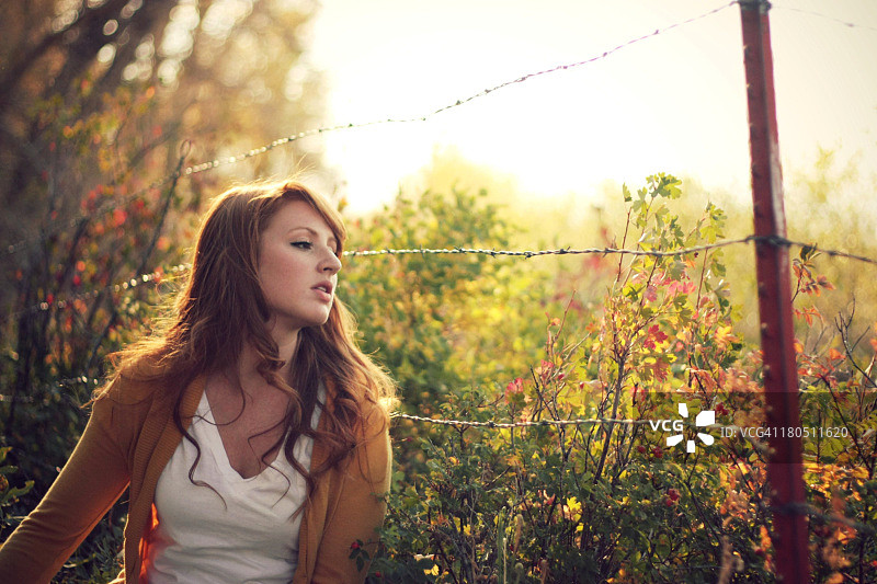 秋天，铁丝网围栏旁的长发女子图片素材