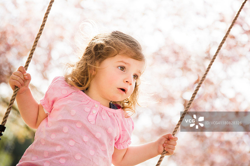 小女孩在公园里荡秋千图片素材