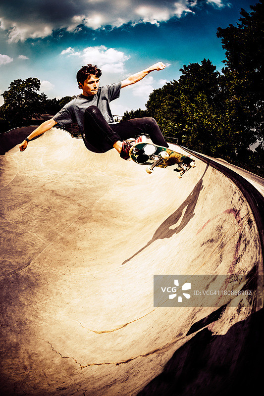 在滑板公园高高跳跃的滑板运动员图片素材