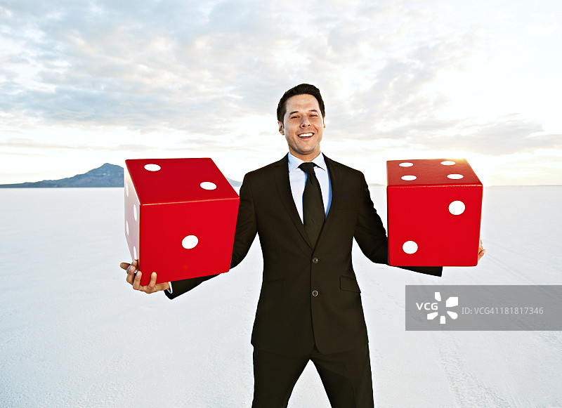 商人手持巨大骰子，面带微笑图片素材