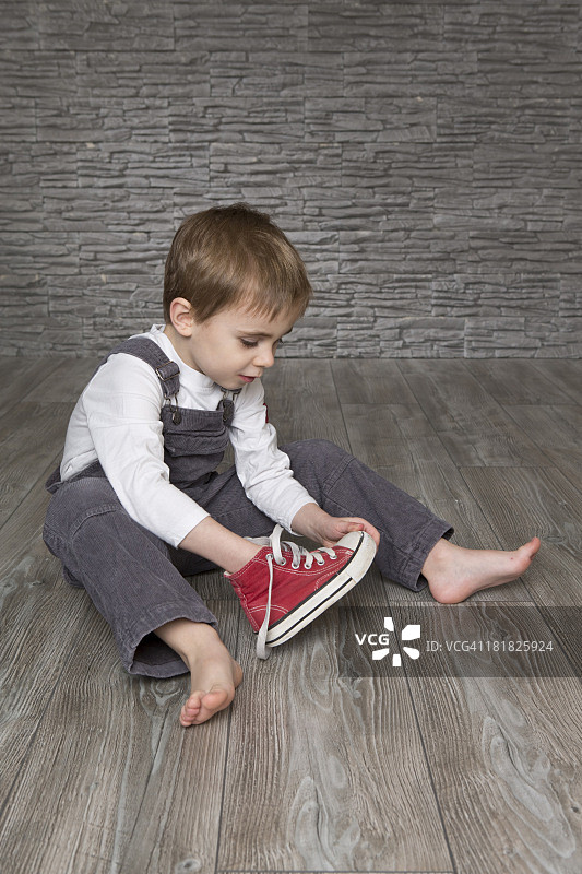 男孩坐在地板上穿鞋图片素材