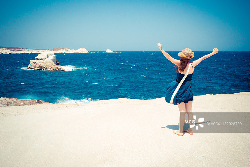 在白色岩石上眺望大海的年轻女子图片素材