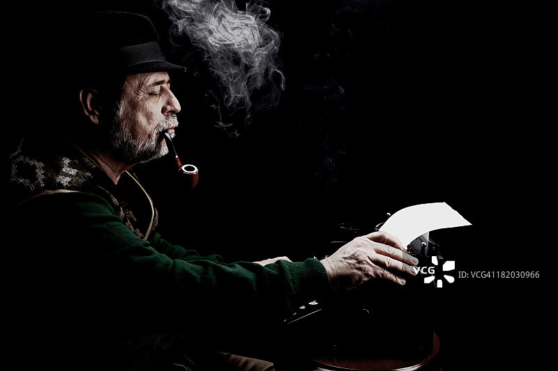 抽烟斗的老年作家与打字机图片素材