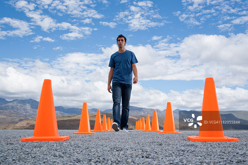 男人行走在两排安全锥之间图片素材