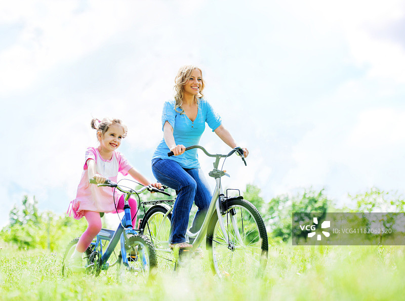 快乐的母女在公园里骑自行车图片素材