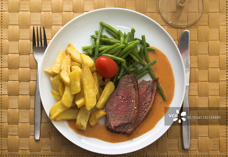 编织餐垫上的牛排蔬菜套餐图片素材