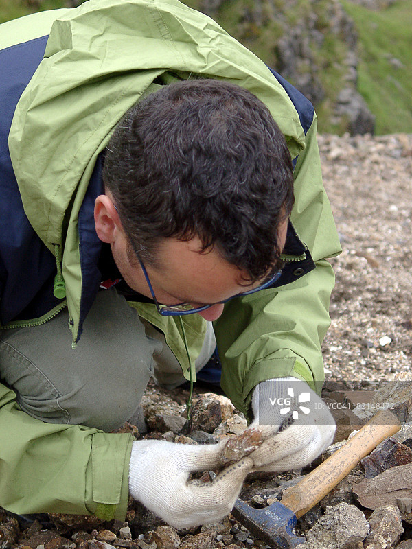 在采石场仔细观察岩石样本的男性地质学家图片素材