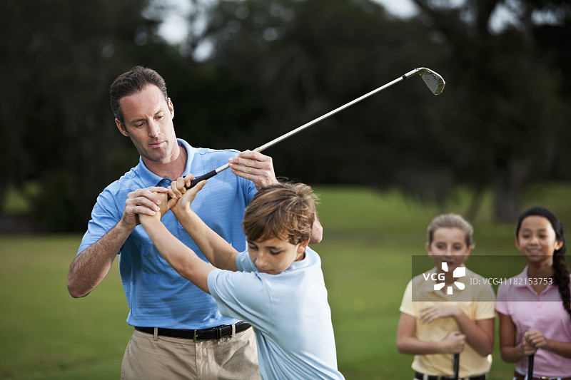 高尔夫教练调整男孩的握杆图片素材