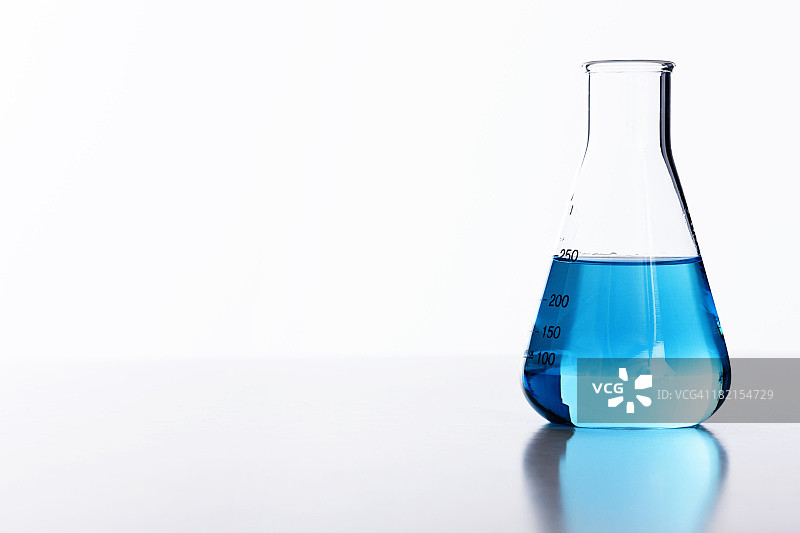 白色背景下，盛有蓝色液体的半满实验室烧瓶图片素材