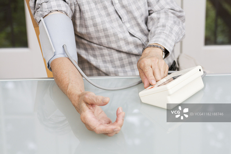 年长者在家中使用血压计监测健康图片素材