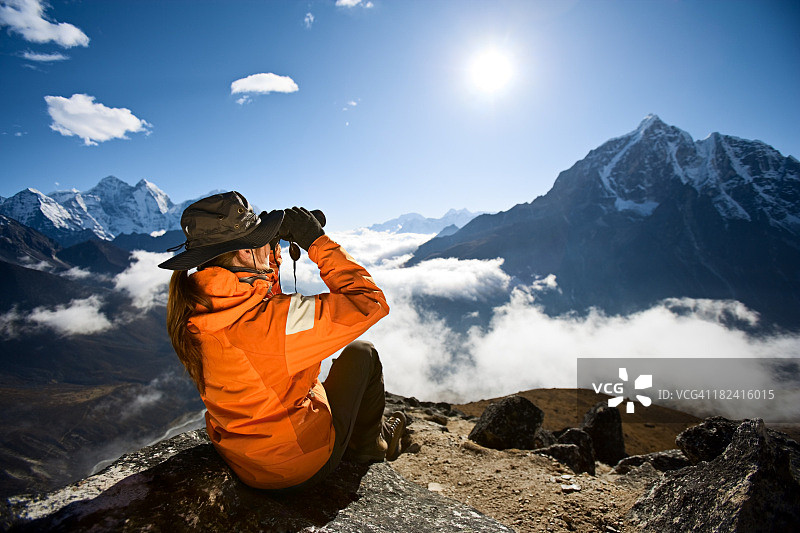 用双筒望远镜观察塔波切峰的女人，萨加玛塔国家公园图片素材