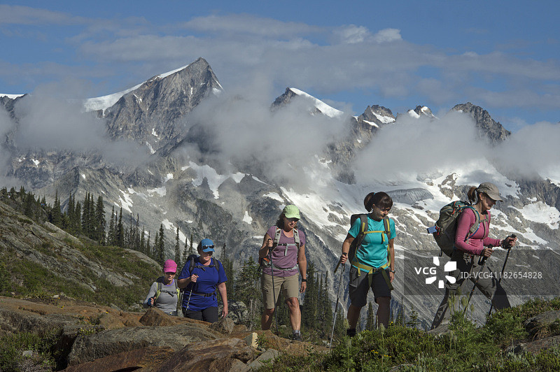 女性团体徒步穿越雾气缭绕的山间草地图片素材
