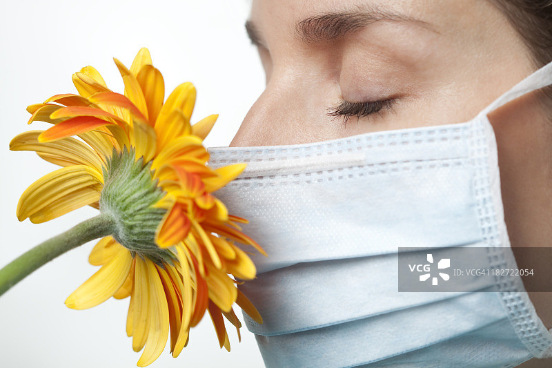 过敏，戴着外科口罩闻花香图片素材
