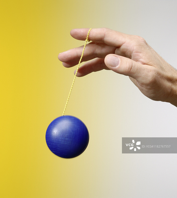 男人在黄色背景上玩蓝色溜溜球图片素材