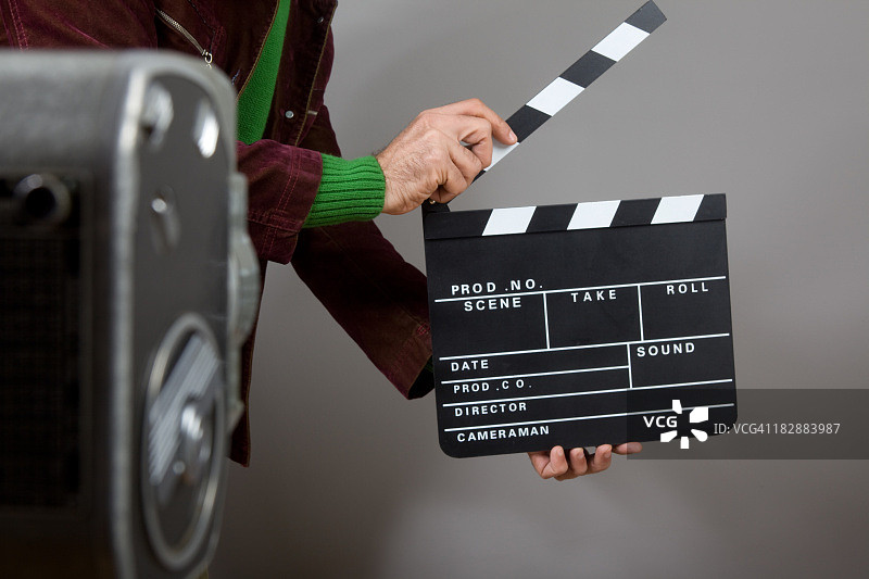 男人在老式相机前手持电影场记板图片素材