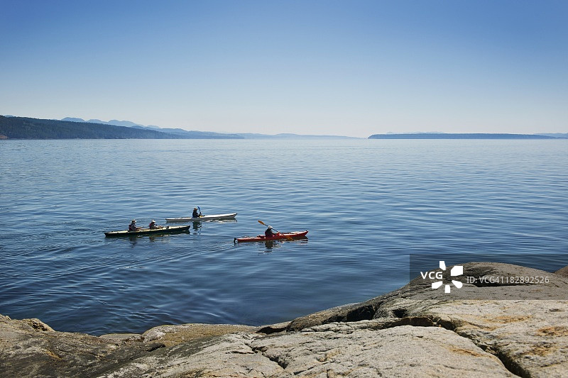 三人沿海岸线划皮划艇图片素材