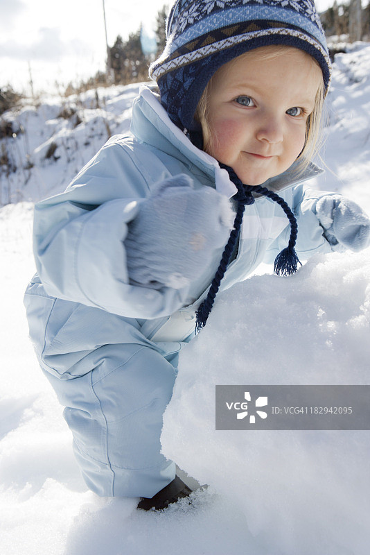 穿着冬装的幼儿女孩堆雪人图片素材