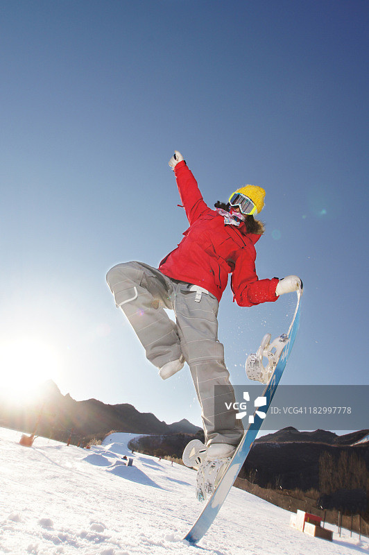 女孩展示单脚站在滑雪板上的技巧图片素材