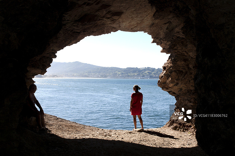 在洞穴边缘看海的女人图片素材