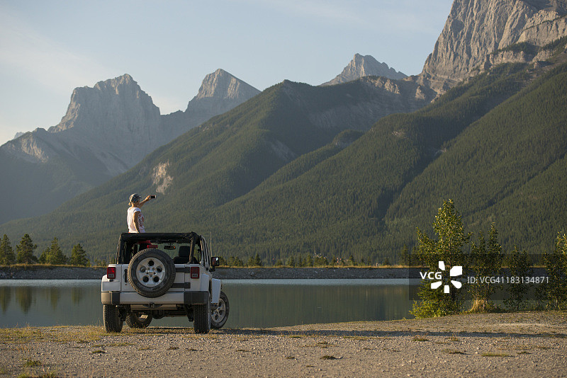 女人在吉普车天窗上拍摄山间湖泊图片素材