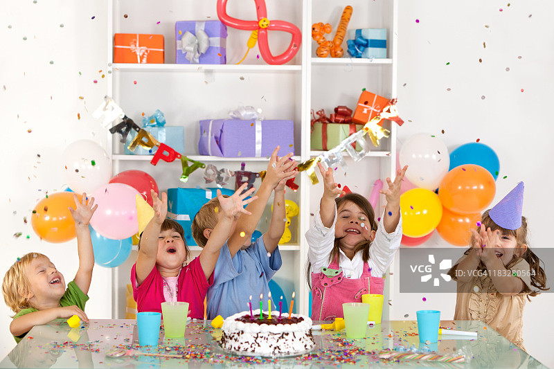 快乐的儿童在生日聚会上接住五彩纸屑图片素材