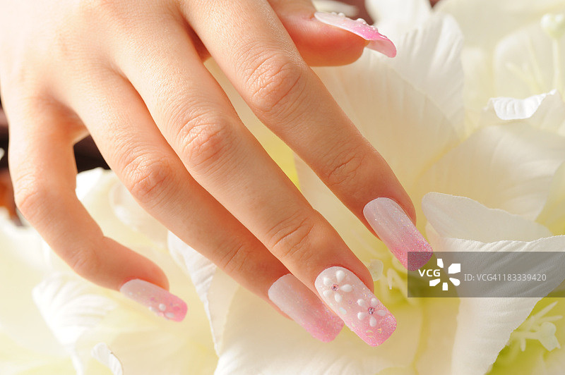 涂有花朵图案的粉色长指甲的女人图片素材