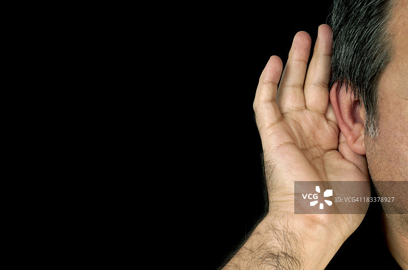 一个人捂住右耳听声音，在黑色背景中隔离图片素材