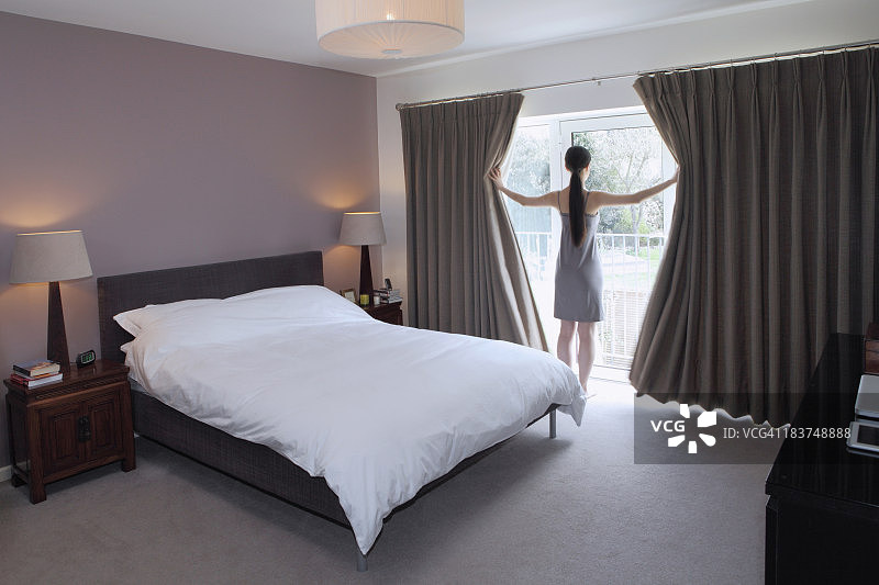 女人拉开卧室的窗帘图片素材