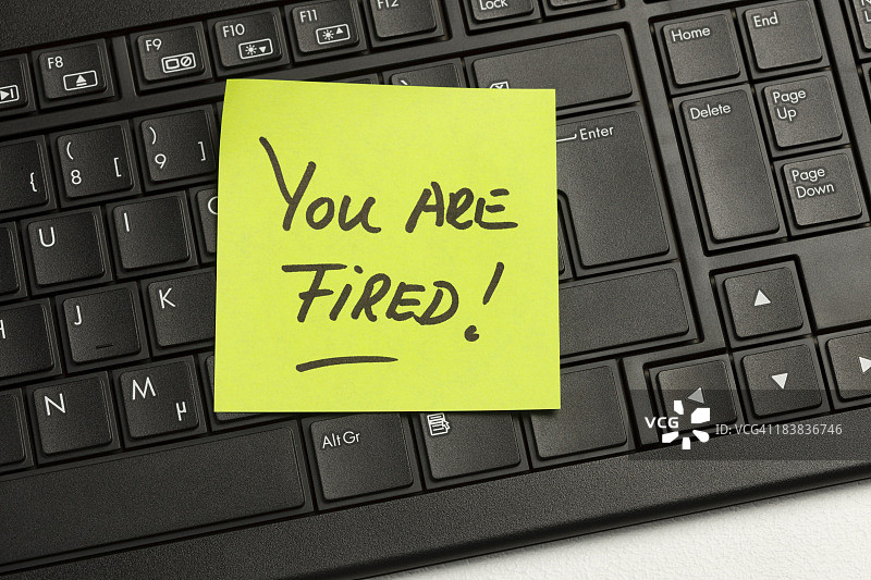 键盘上写着“你被解雇了”的纸条特写图片素材