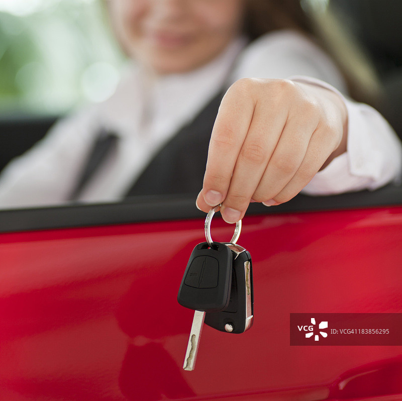 女人坐在车里，拿着钥匙伸出窗外图片素材