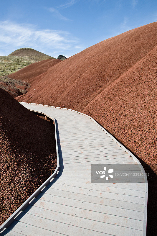 锈色山丘间的弯曲木板路图片素材