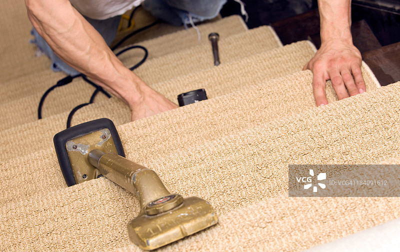 安装工人用撑膝器固定楼梯地毯图片素材