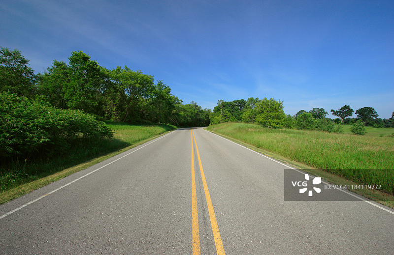 穿过阳光明媚乡村的道路图片素材