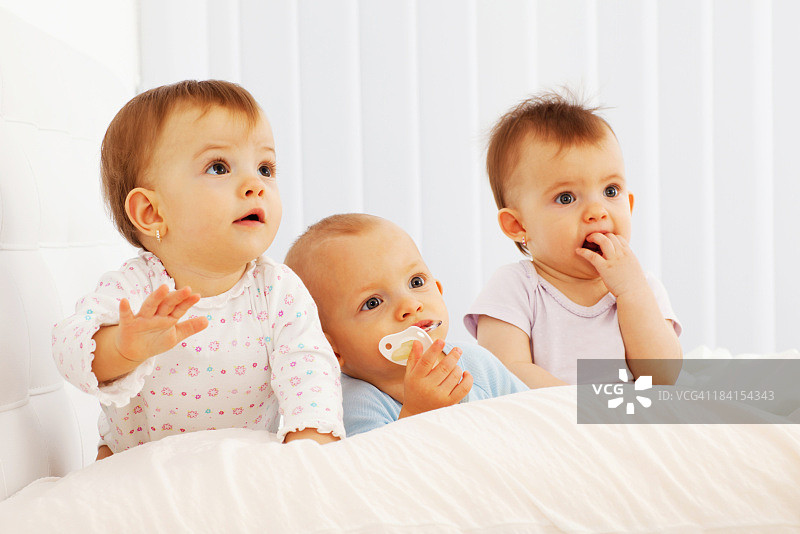 可爱的三胞胎宝宝躺在床上图片素材