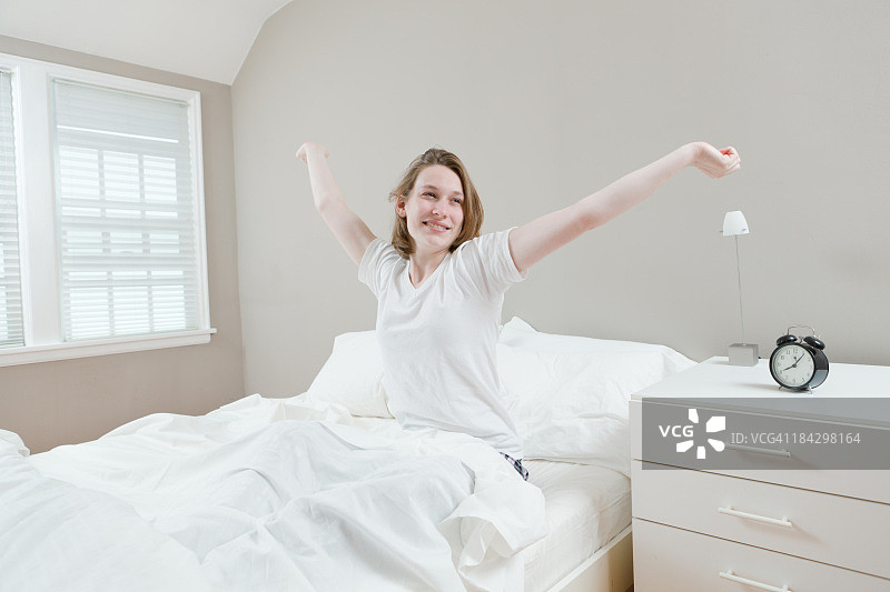 快乐年轻女人在床上醒来感觉良好图片素材