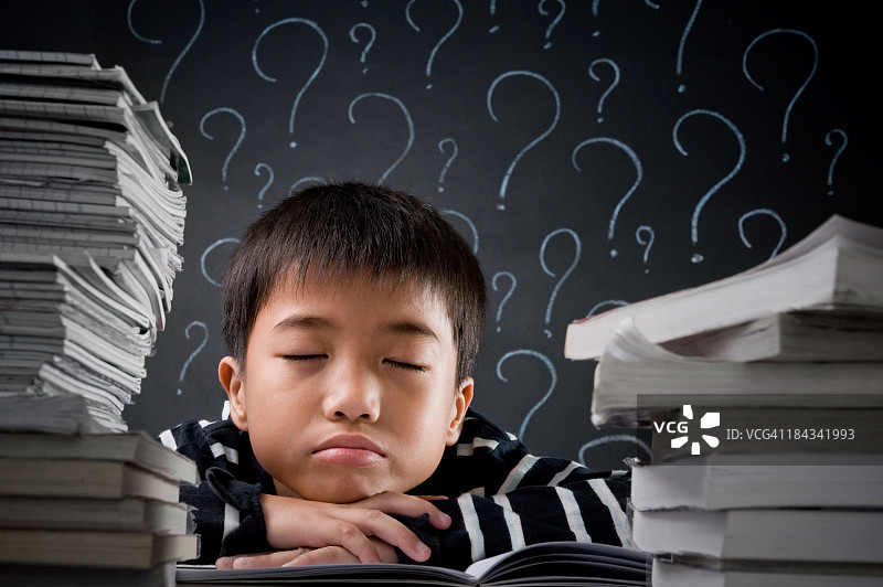 小男孩坐在书堆中图片素材